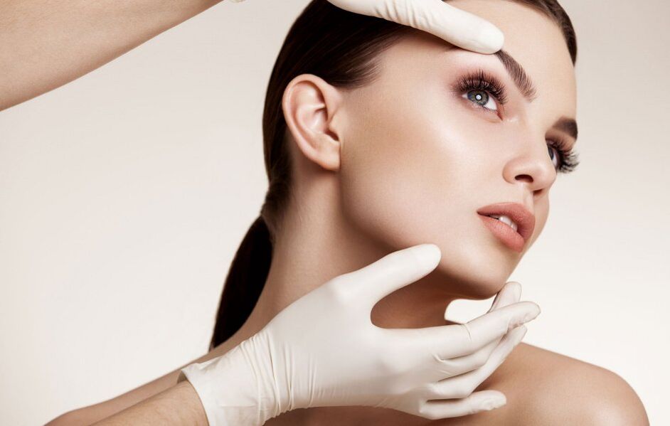 the beautician examines the facial skin before rejuvenation